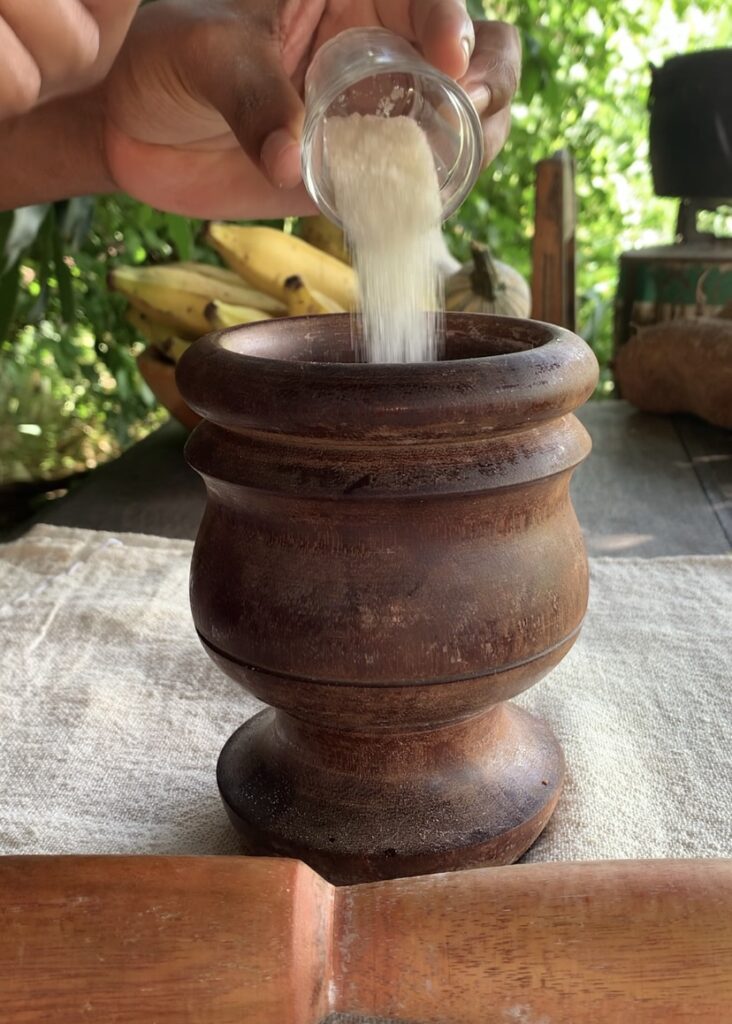 Pilão de madeira sendo dispejado açúcar em seu interior